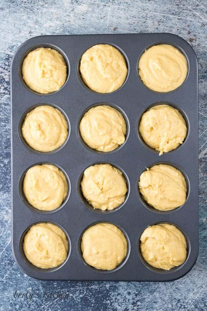 A large muffin tin filled with the cornbread muffin batter.