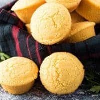 Homemade cornbread muffins in a bowl with a decorative towel.