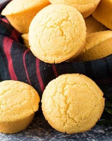 Homemade cornbread muffins in a bowl with a decorative towel.