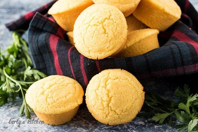 Homemade cornbread muffins in a bowl with a decorative towel.