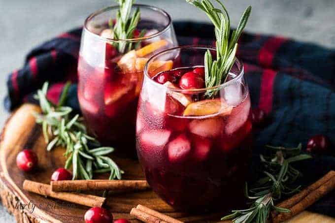 Two stemless wine glasses filled with cranberry sangria and ice.
