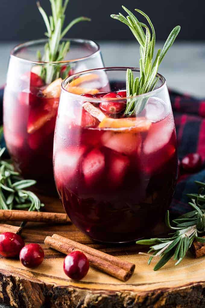 Two glasses of sangria garnished with cranberries and orange slices.