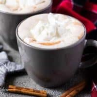 Two mugs of gingerbread hot chocolate topped with whipped cream.