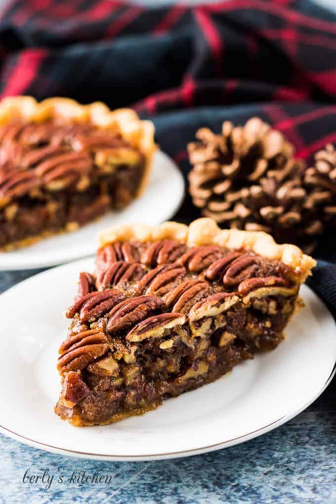 Two slices of pecan pie served on small decorative saucers.