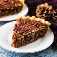 A slice of pecan pie on a small decorative saucer.