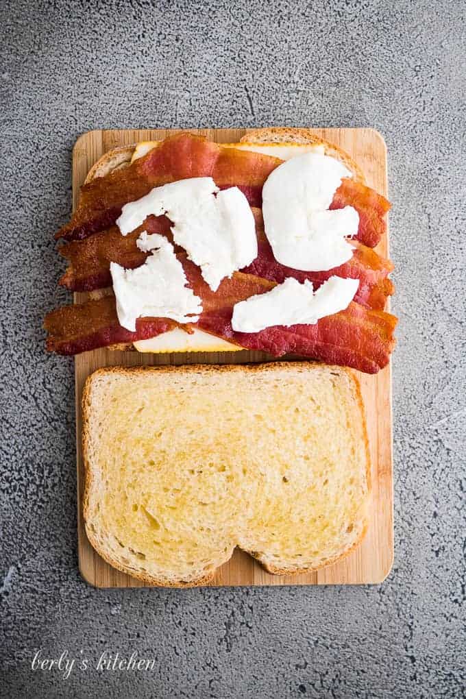 Sliced mozzarella cheese has been placed atop the cooked bacon.