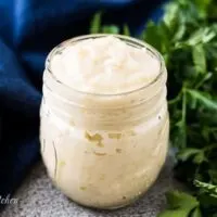 Jar of homemade cream of celery soup substitute next to parsley.