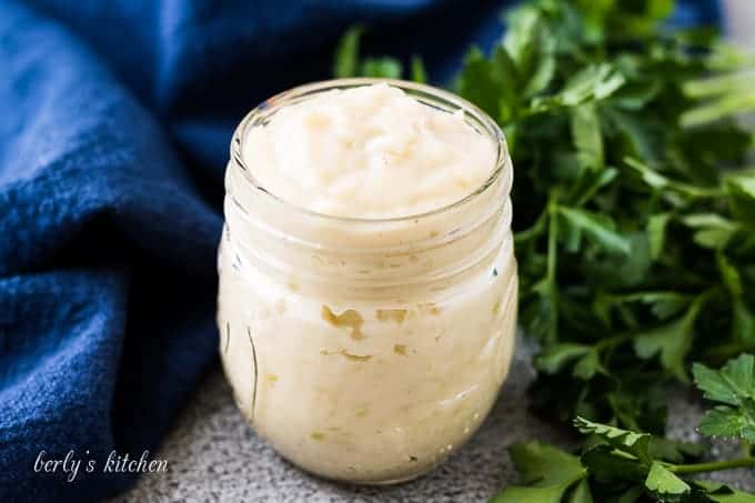 Jar of homemade cream of celery soup substitute next to parsley.