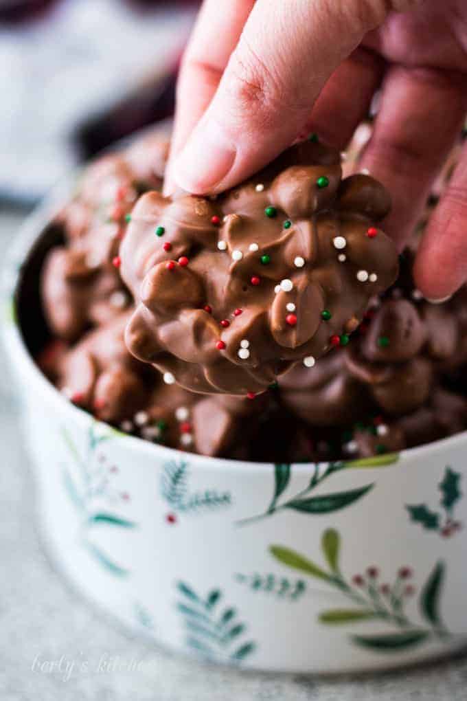 Kim holding a piece of the finished chocolate crockpot candy.