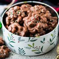 Crockpot candy topped with sprinkles in a decorative cookie tin.