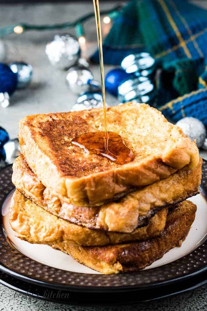 A stack of french toast being drizzled with maple syrup.