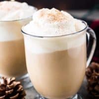 Two finished eggnog latte coffee drinks served with whipped cream.