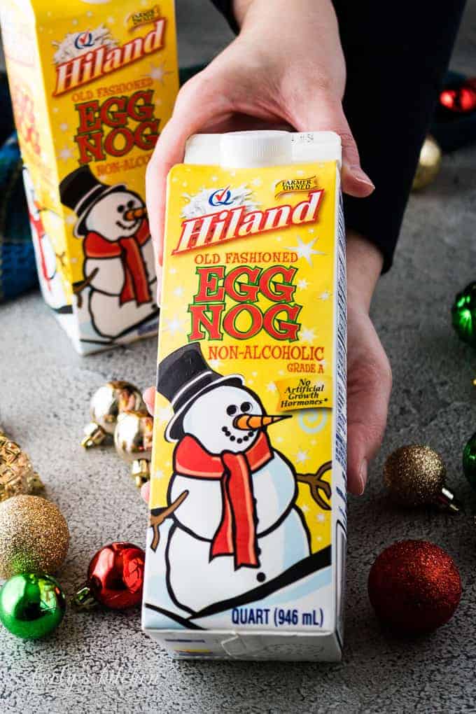 Kim holding an unopened carton of hiland dairy brand eggnog.