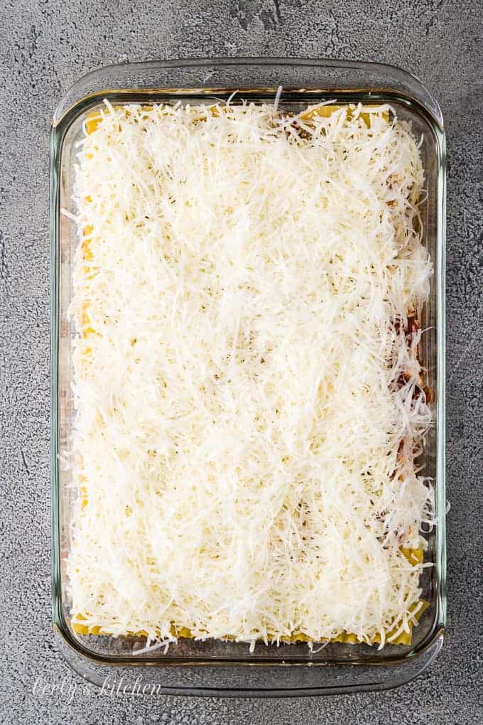 Shredded mozzarella and parmesan cheese top off the unbaked lasagna.