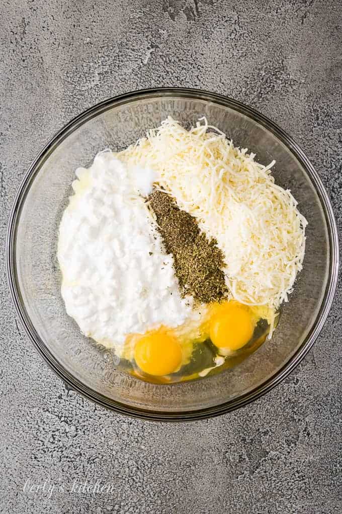 Mozzarella cheese, eggs, and spices in a large mixing bowl.