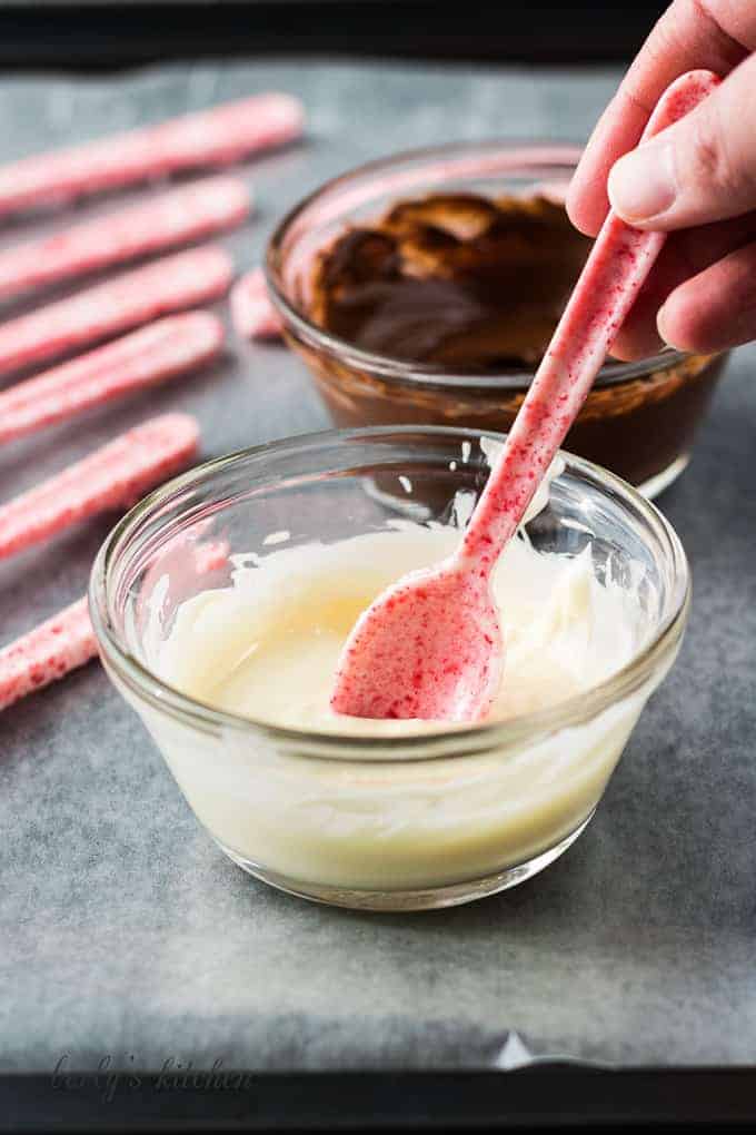 One of the candy spoons being dipped into white chocolate.