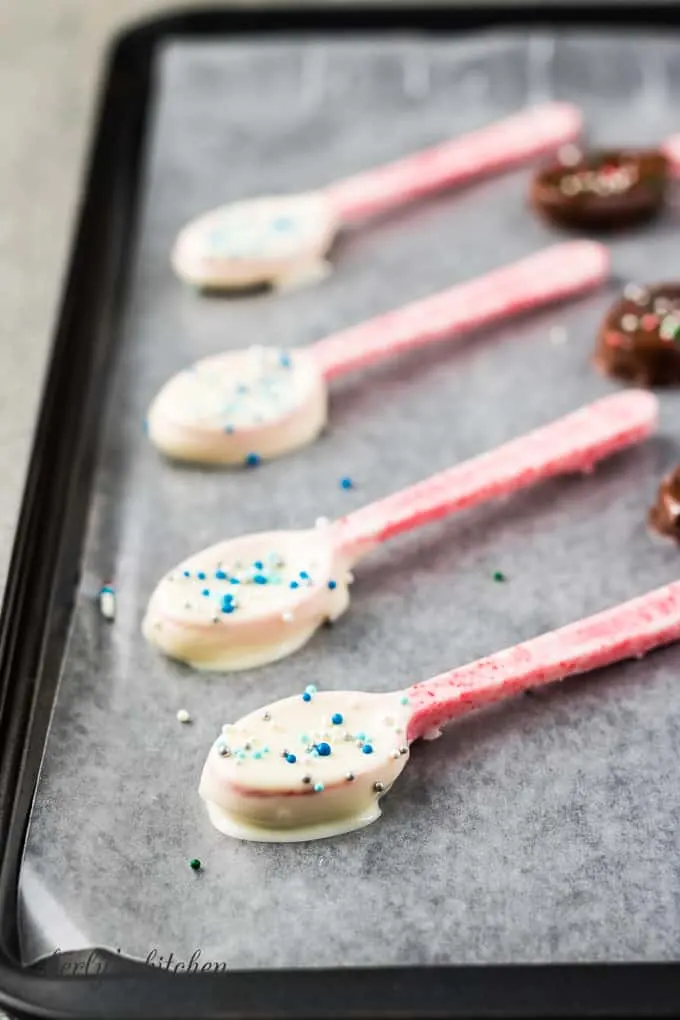 The chocolate dipped spoons, with sprinkles, cooling on wax paper.