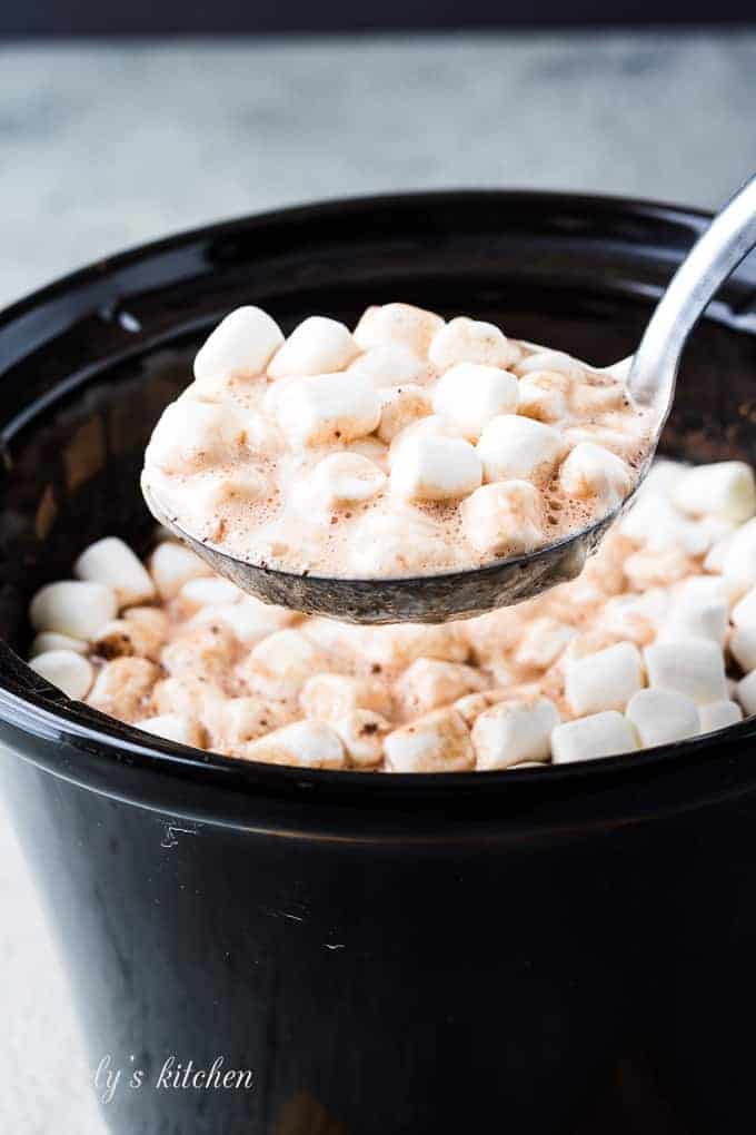 A large ladle of the cocoa topped with melting marshmallows.