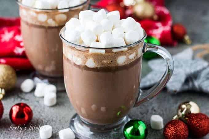 Two mugs of slow cooker hot chocolate topped with marshmallows.