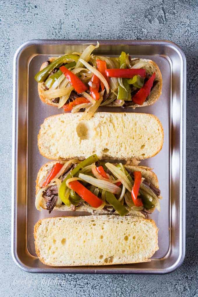 Shredded beef, onions, and peppers on a sliced hoagie bun.