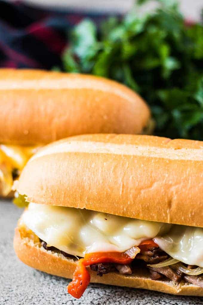 A philly cheesesteak with sliced provolone on a toasted bun.
