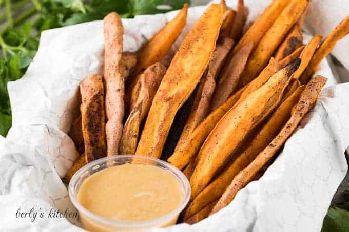 Sweet potatoes fries in a basket with maple butter dipping sauce.