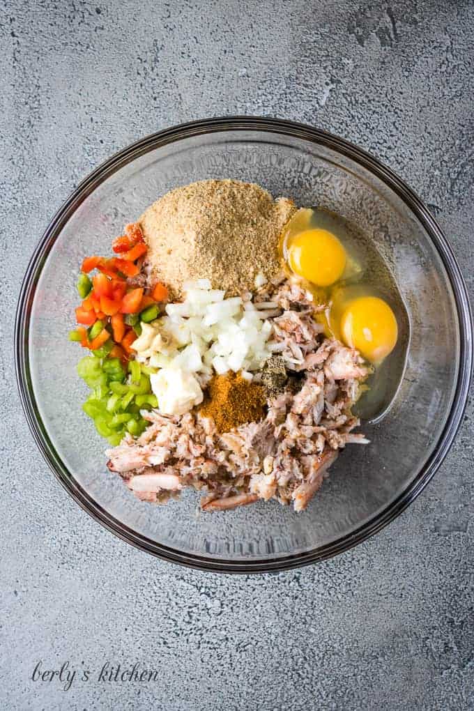 Crab, eggs, and other ingredients in a mixing glass bowl.