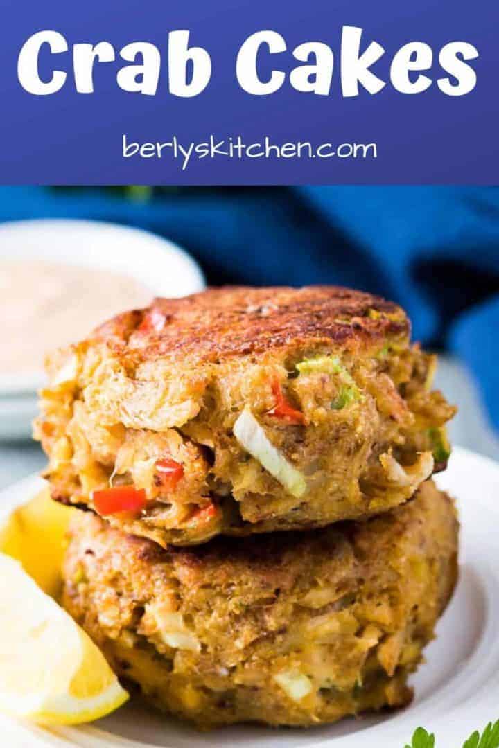 Homemade Crab cakes stacked on a plate with lemon wedges.