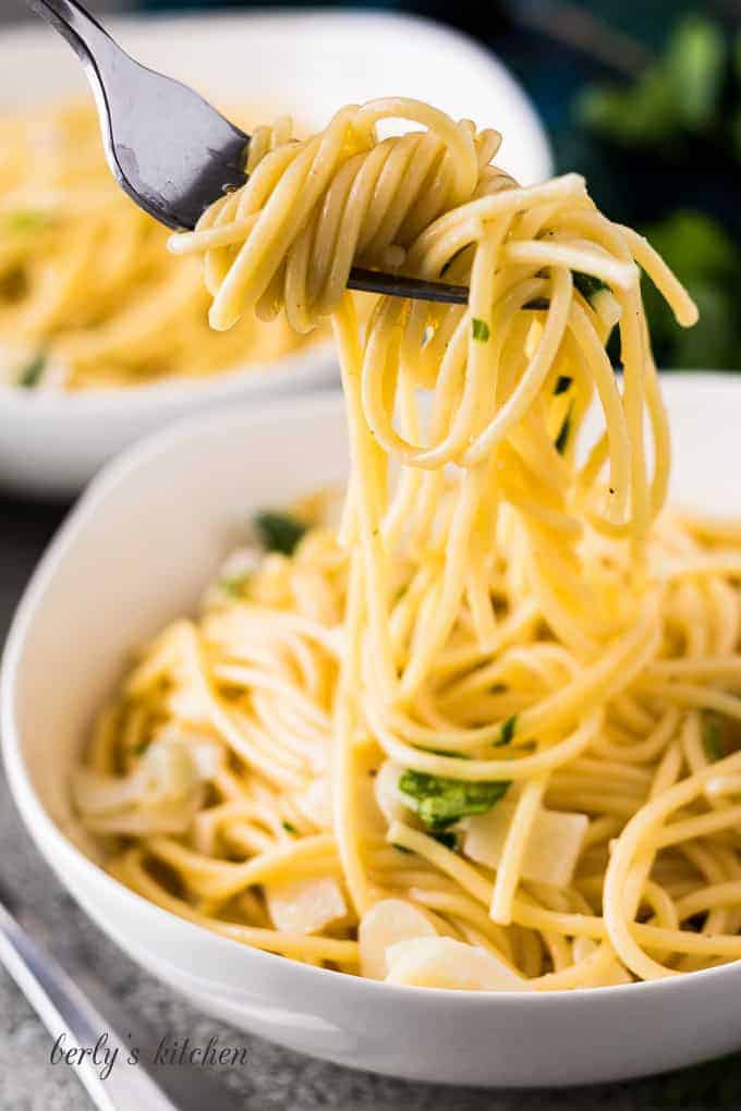 A fork twirling the noodles to show the fresh garlic..