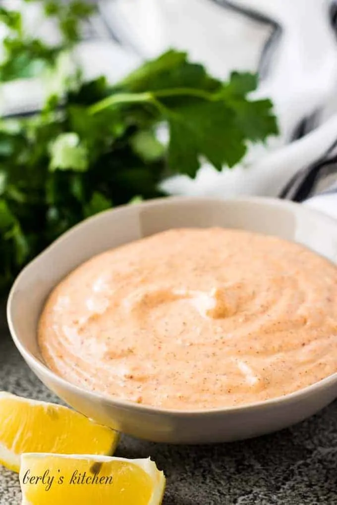 Two lemon wedges next to a bowl of the sauce.
