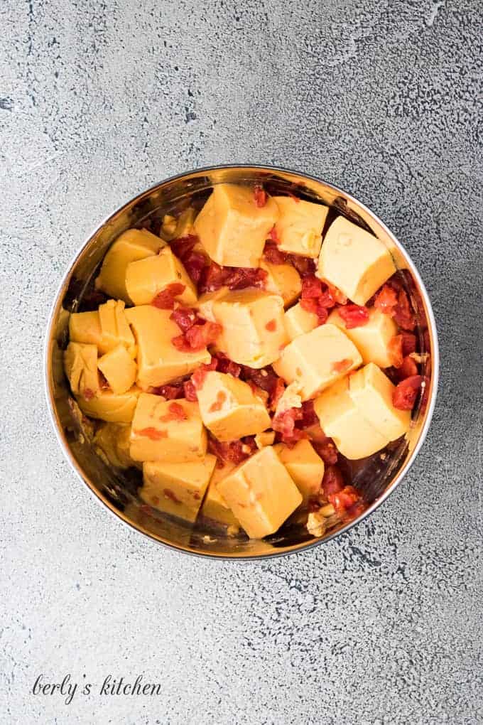 Cubed velveeta, diced tomatoes and chiles in a metal bowl.