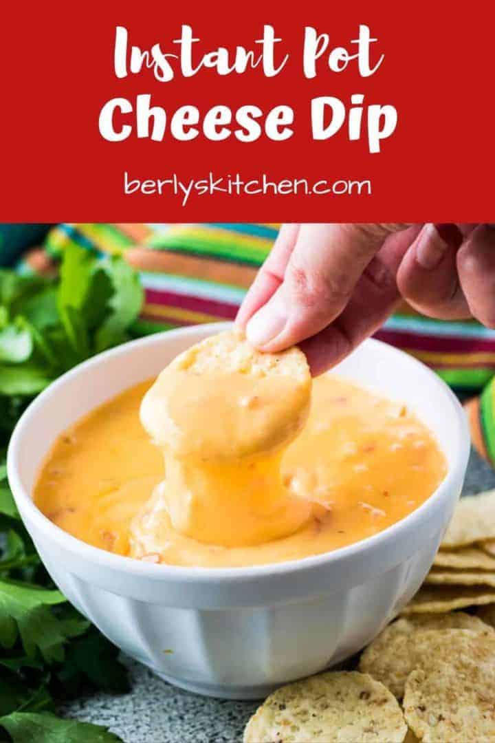 A tortilla chip being dipped into the instant pot cheese dip.