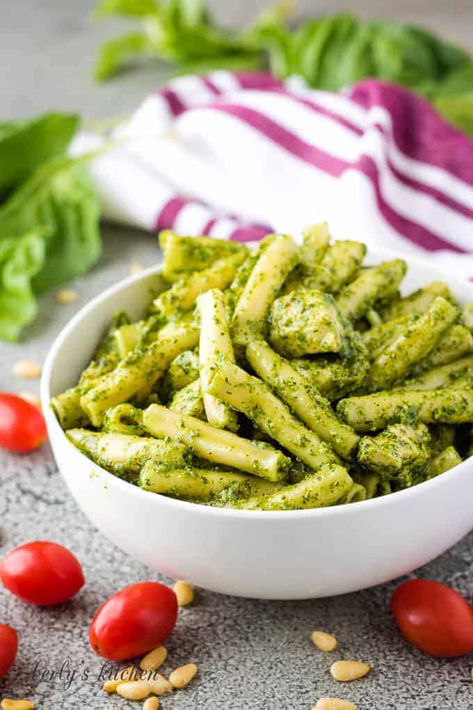The pesto pasta in a bowl surrounded by cherry tomatoes.