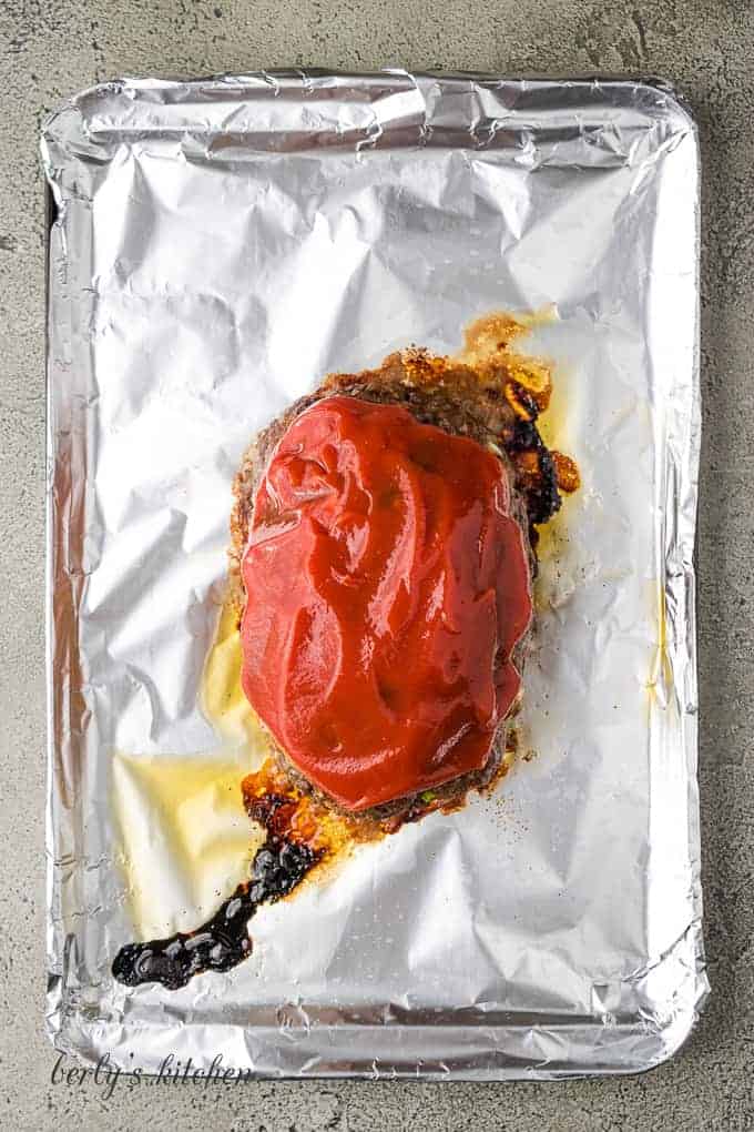 Tangy ketchup has been placed on top of the meatloaf.