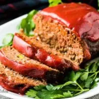 The sliced meatloaf on a platter and topped with ketchup.