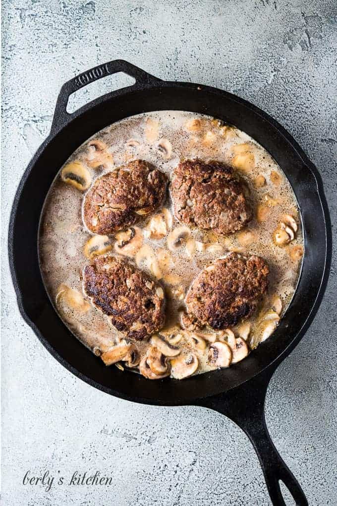 The patties placed back into the pan with the mushroom gravy.