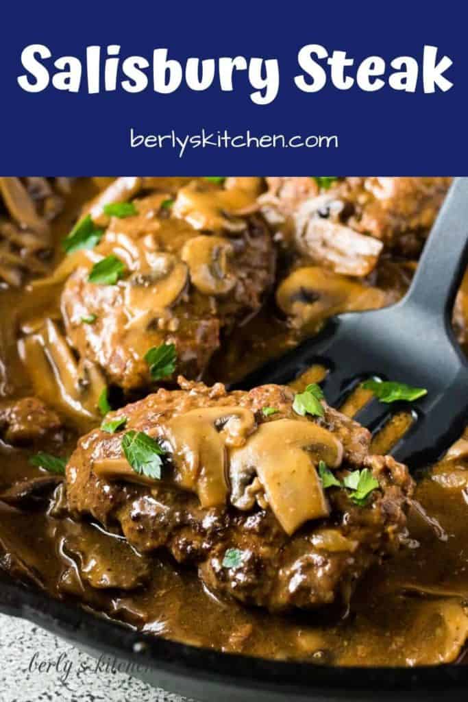 Salisbury steak covered in mushroom gravy being lifted from the pan.