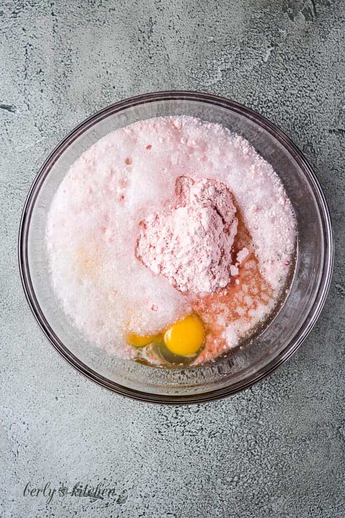 Strawberry cake mix, eggs, and oil in a mixing bowl.
