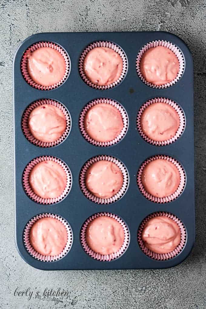 Strawberry cake mix cupcake batter transferred to decorative red liners.