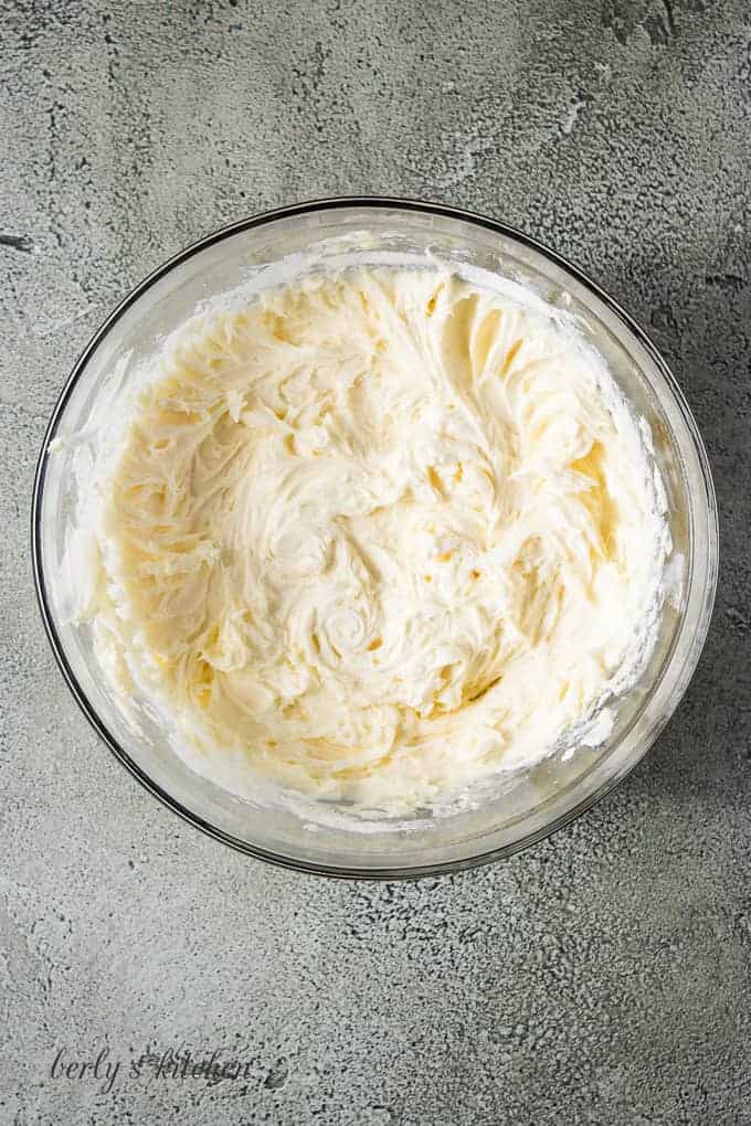 Powdered sugar, champagne, and butter combined in a mixing bowl.