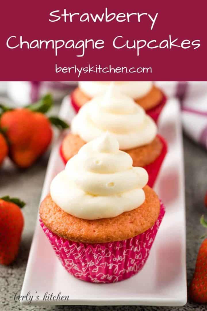 The strawberry champagne cupcakes in liners on a rectangular plate.