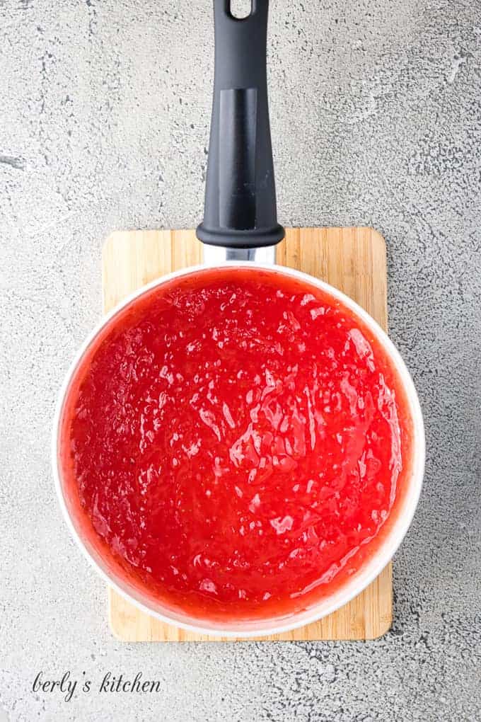 One cup of pureed strawberries in a large metal saucepan.