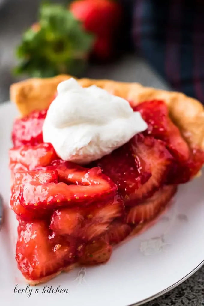 A large slice of pie showing all the fresh strawberries.