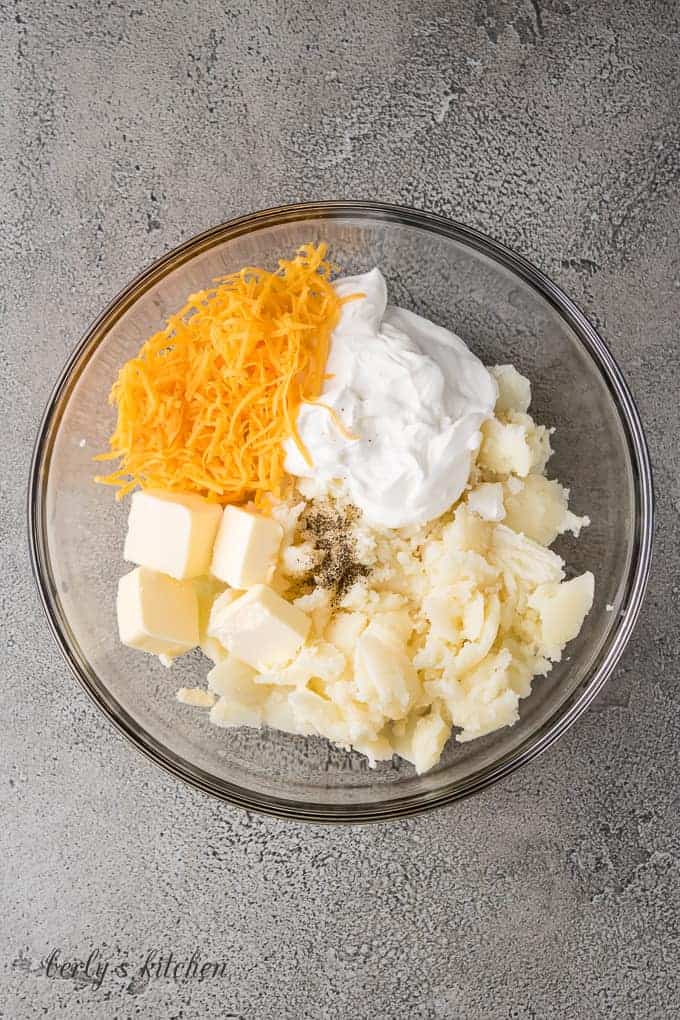 Potatoes, butter, sour cream and cheese in a mixing bowl.