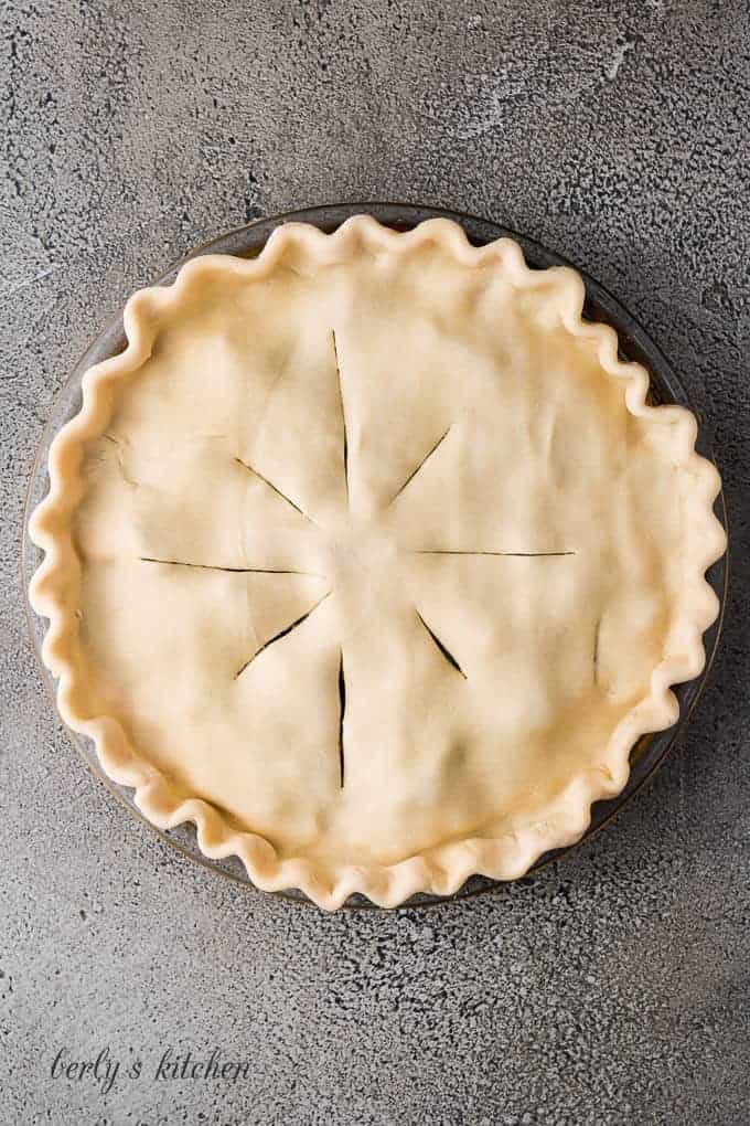 Unbaked pie crust, with vents cut, covering the pie filling.