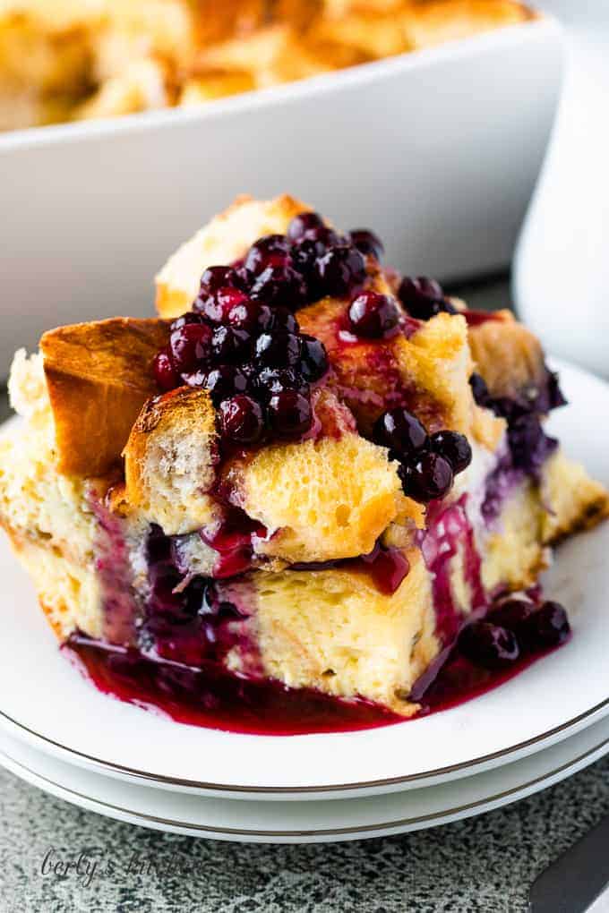 A big piece of french toast casserole topped with blueberry sauce.