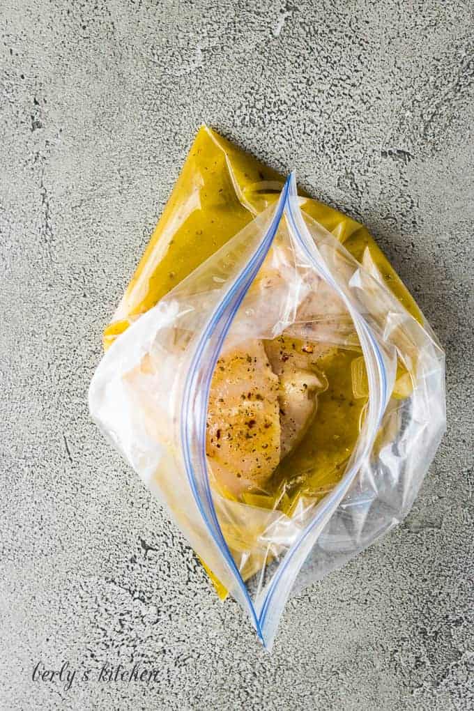 Raw chicken breasts and italian dressing in a freezer bag.