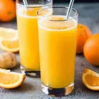 Two glasses of the fizzy orange drink with colorful straws.