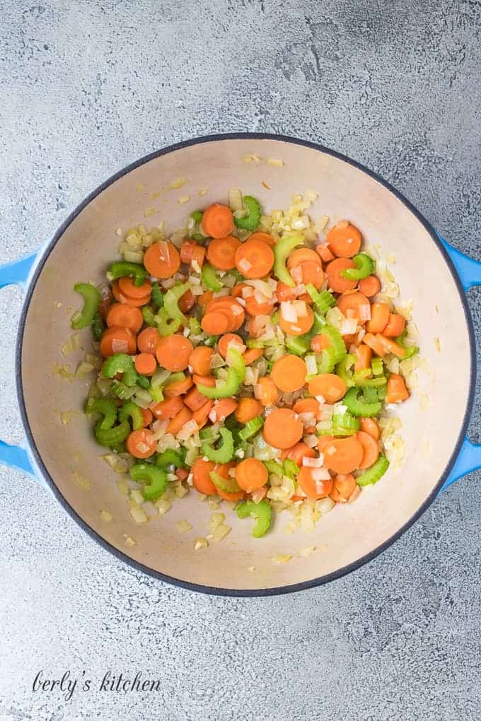 Carrots, celery, and onions in a large blue Dutch oven.