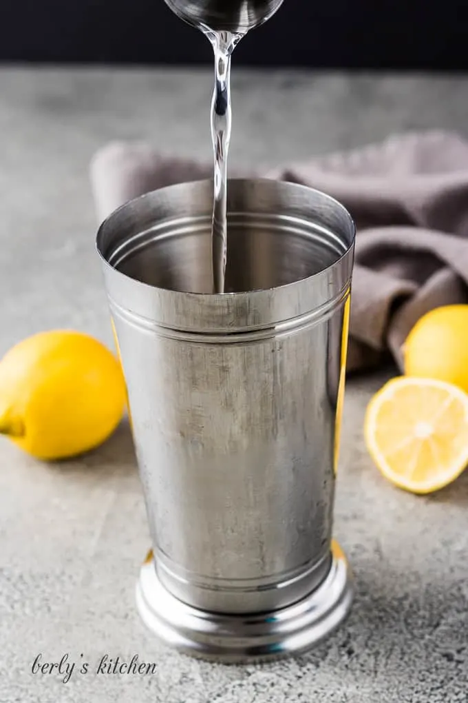 Regular vodka being poured into a shaker filled with ice.
